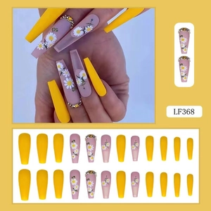 Long coffin fake nails featuring matte pink daisy designs with rhinestones and yellow colors
