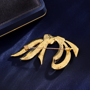 Vintage gold ribbon bow brooch with hammered texture on a luxury silk background