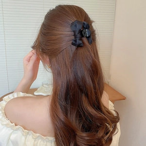 Dettaglio di un elegante fermaglio per capelli con fiocco nero su acconciatura