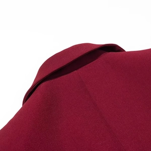 Detail of burgundy blazer showing shoulder stitching and textured woven fabric quality