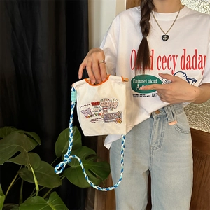 Détail du mini sac en toile blanche avec imprimés graffiti et poignées en coton tressé