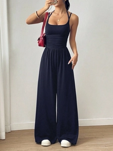 Detail of waist pleats and smocked elastic gathering on black wide-leg jumpsuit