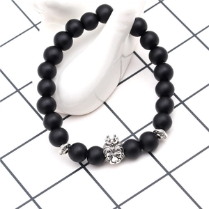 Close-up of matte black beads bracelet with a silver lion head crown charm on hand
