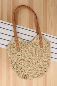 Close-up of beige woven tote bag with V-pattern texture and reinforced brown leather straps