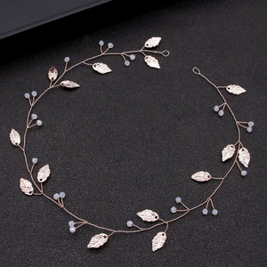 Handmade golden leaf bridal hair comb with white beads on black textured background