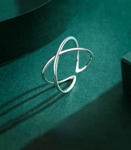 Macro shot of 925 sterling silver X-shaped cross ring on textured dark green surface