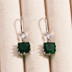Détail de boucles d'oreilles dorées 18K avec des cristaux de zircone carrés vert émeraude