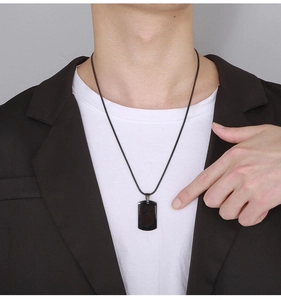 Close-up of a black stainless steel military style pendant necklace worn by a model