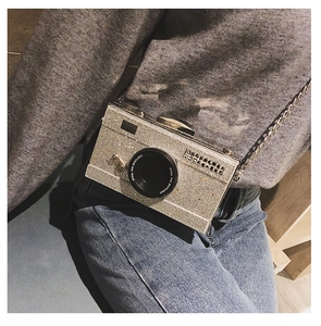 Detailed view of silver sequin camera bag with metal chain strap worn by a model