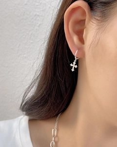 Close-up of S925 sterling silver cross earring with shimmering zircons on model ear
