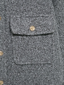 Close-up of grey sherpa jacket featuring textured wool fabric and an embossed gold button