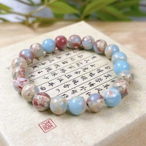 Zen style beaded bracelet with light blue and reddish-brown stone beads on a textured box