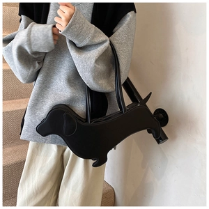 Chic black dachshund-shaped leather shoulder bag worn by model on stairs