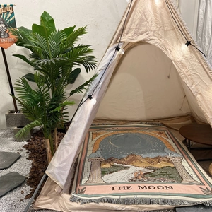 Detail of woven Bohemian Moon tarot blanket with tassels inside a cozy camping tent