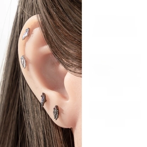 Detailed view of silver angel wing ear studs featuring intricate feather textures and zircon