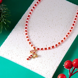 Macro detail of Christmas candy cane necklace with red white beads and gold bow decoration
