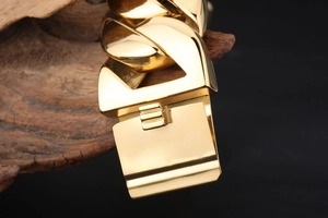 Macro shot of the polished gold-plated buckle on a bold stainless steel Cuban link bracelet