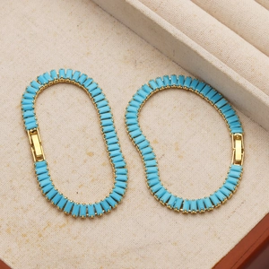 Macro detail of turquoise-toned rectangle gemstones set in 18K gold plated prong setting