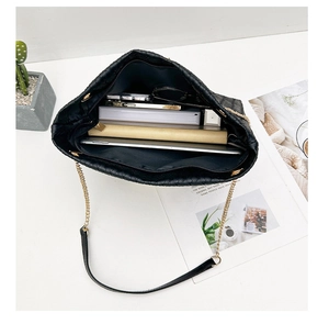 Top view of black woven tote bag interior showing ample storage and gold chain strap