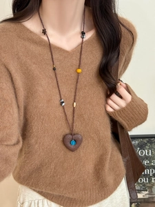 Detail of stone heart pendant necklace with blue bead on a long beaded sweater chain