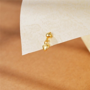 Macro shot of minimalist gold heart-shaped stud earring with spherical post detail