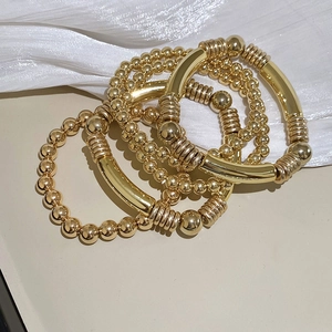 Détail macro d'un ensemble de quatre bracelets dorés avec des perles en métal poli