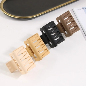 Detail view of four matte square hair claws in beige, brown, and black on a white surface