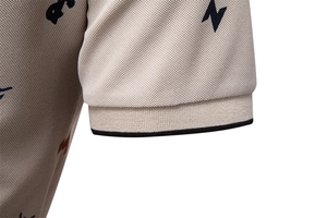 Dettaglio della manica di polo in piqué beige con polsini a costine e riga nera