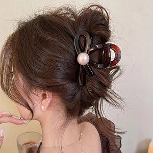 Brown bow hair claw clip with centered pearl on hair for minimalist hair styling