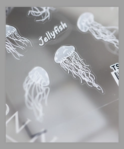 Macro detail of delicate white jellyfish nail art stickers with fine lines on clear base