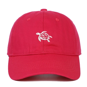 Close-up of white turtle embroidery with scroll patterns on a dark red cotton baseball cap