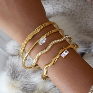 Macro detail of four stacked 18K gold plated bracelets featuring zircon and hammered texture