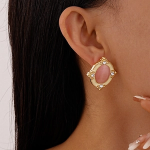 Close-up of vintage gold earring with pink cat-eye stone and rhinestones on model