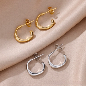 Close-up of gold and silver triple-layered C-shaped hoop earrings on beige silk fabric