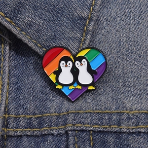 Cartoon rainbow heart penguin enamel pin badge accessory on dark blue denim fabric