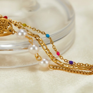 Macro shot of gold stainless steel multi-layer bracelet with pearls and heart charms
