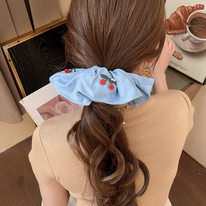 Detail of light blue satin scrunchie with cherry embroidery and pearl accents on hair