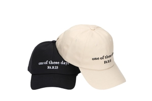 Detailed view of black and beige cotton baseball caps with embroidered text