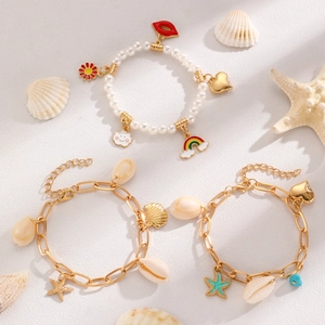 Detail view of Bohemian seashell and starfish charm bracelets on a beach sand background