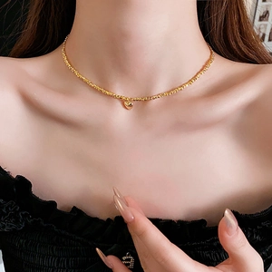 Close-up of golden beaded necklace featuring a delicate heart pendant on model