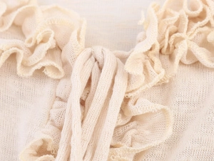 Macro shot of fine beige knitted fabric with ruffled edges and soft texture detail