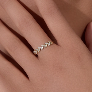 Elegant gold wheat leaf ring with sparkling diamonds shown on finger in a macro view
