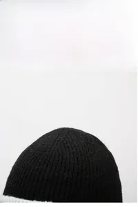 Gros plan du bonnet en maille côtelée noire montrant la texture rayée et la laine douce