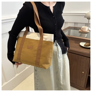 Close-up of a large canvas tote bag in brown and cream, styled in a cozy indoor setting