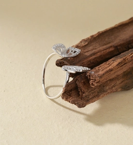 Macro shot of silver dual butterfly ring with pave-set zircons on a wooden prop