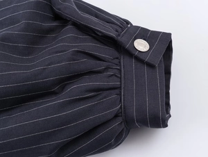 Dettaglio del polsino della giacca gessata blu navy con bottone in metallo argentato lucido