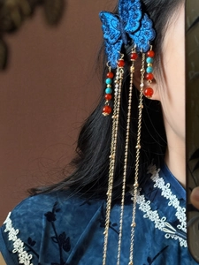 Détail de la pince à cheveux papillon bleu brodé avec de longues franges dorées sur modèle