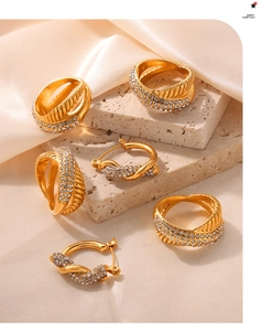 Close-up of gold-plated rings and earrings set with crystal pavé on travertine stones