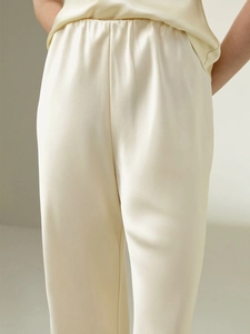 Close-up of cream satin pants showing smooth silk-like texture and elastic waistband details