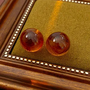 Close-up of vintage amber resin round bead earrings on a premium coffee fabric lining